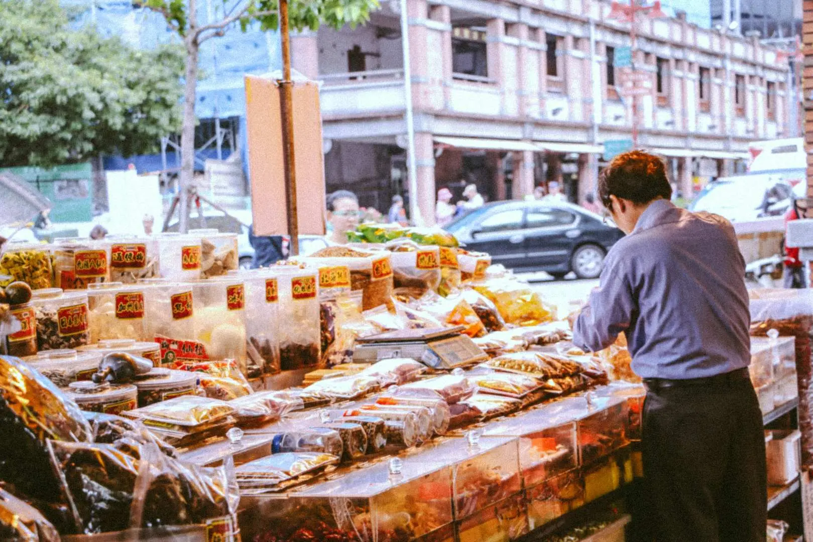 A vendor arranging traditional Chinese herbs and dried goods at a bustling stall on Dihua Street in Dadaocheng, Taipei, an iconic scene from the walking tour.