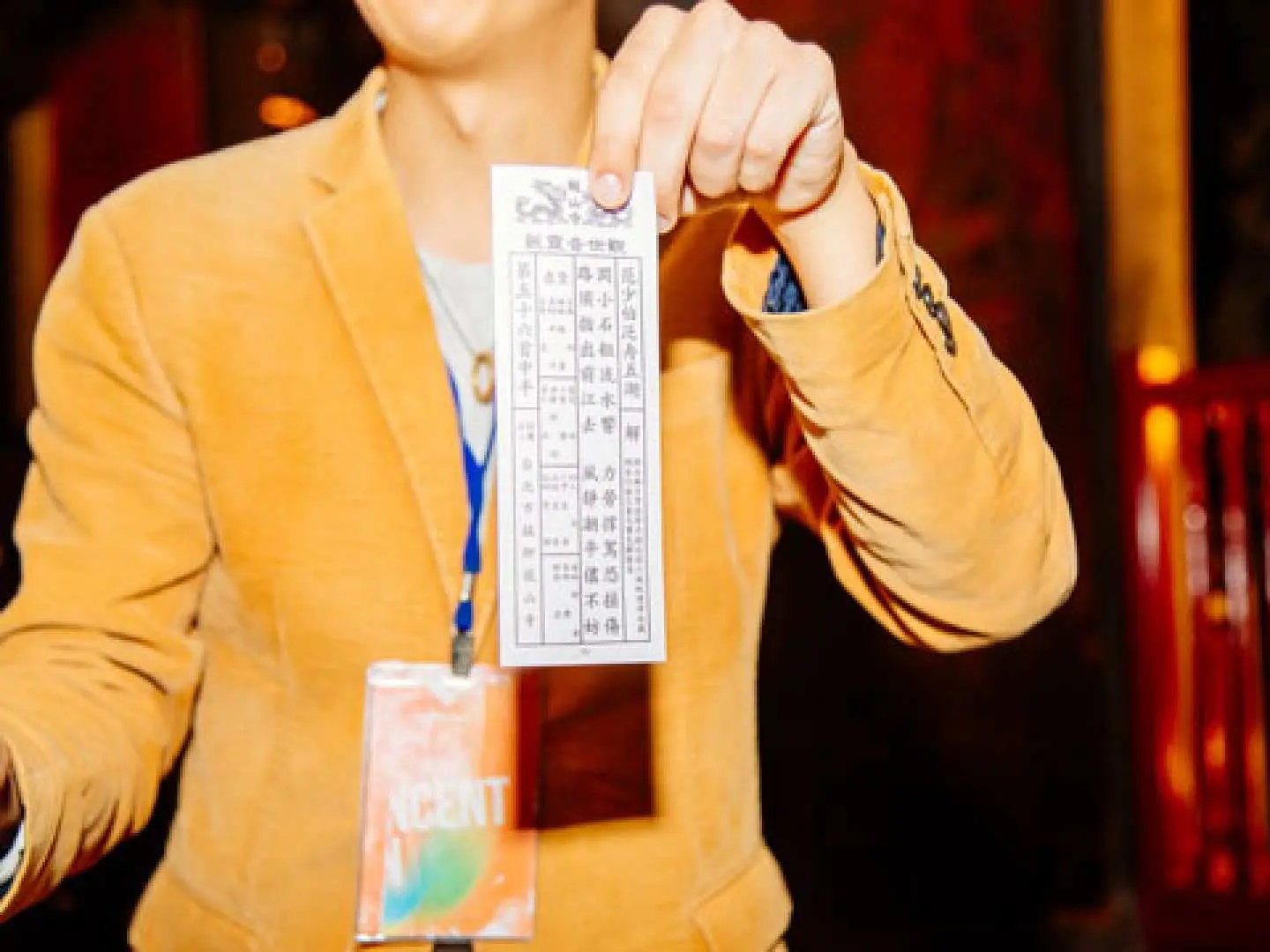A guide holding a divination slip at Longshan Temple, explaining Taiwan's traditional fortune-telling culture to tour participants.