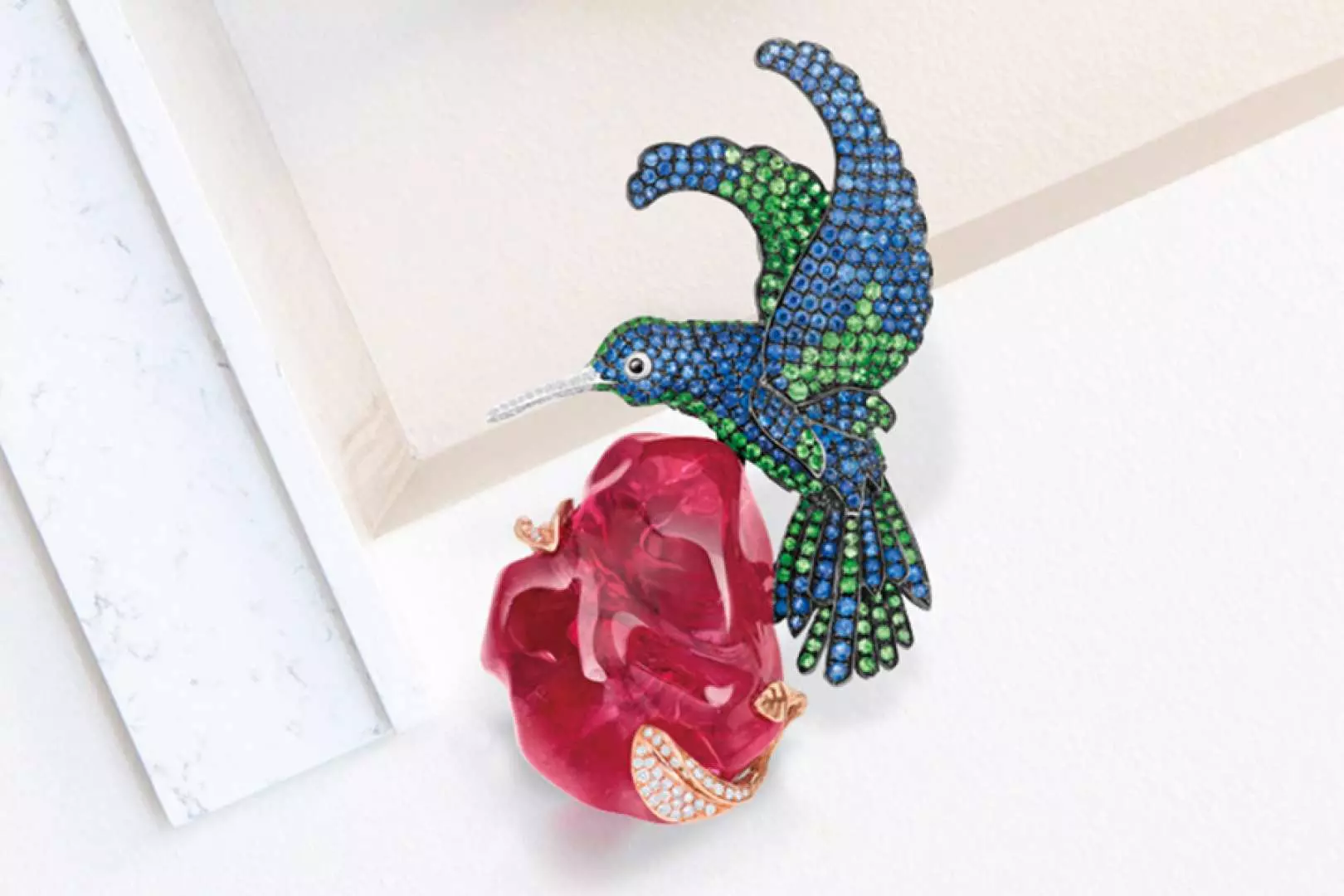 Inside Taoyuan Jurassic Museum's exhibition, an exquisite hummingbird-shaped gemstone brooch next to a sparkling ruby, showcasing the museum's diverse collection of precious minerals.