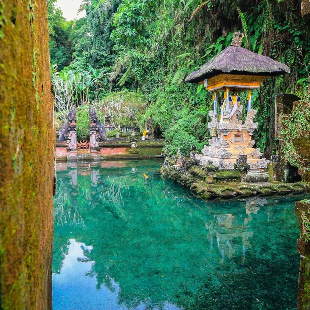 峇裡島烏布普拉古農卡維寺廟清澈翠綠的聖水池，精美小神龕矗立池畔，周圍熱帶植物環繞，營造寧靜氛圍。