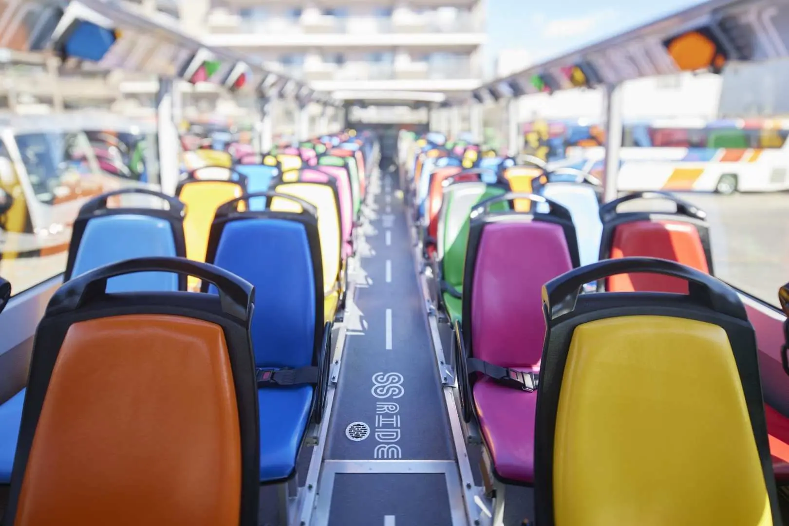 Spacious upper deck seating area of the Tokyo double-decker open-top bus, with colorful seats and clear S.S. RIDE branding on the floor, providing a comfortable environment for Shibuya sightseeing.