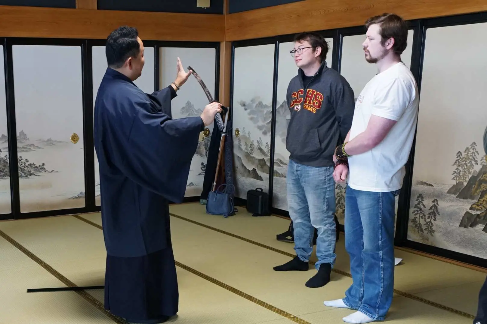 在宮崎縣盛岡城的日式榻榻米房間內，遊客專注聆聽指導員講解日本刀的使用與武士歷史文化。