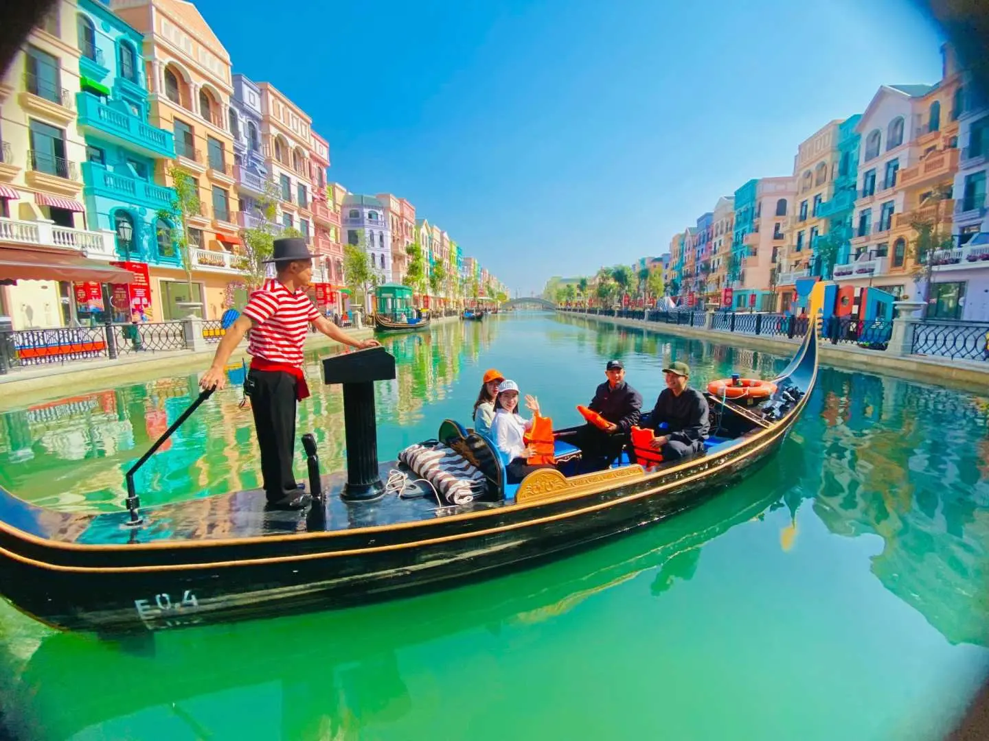 Visitors enjoy a leisurely gondola ride through Hanoi Grand World's expansive Venetian-style canal, with dazzling European buildings lining both sunny banks.