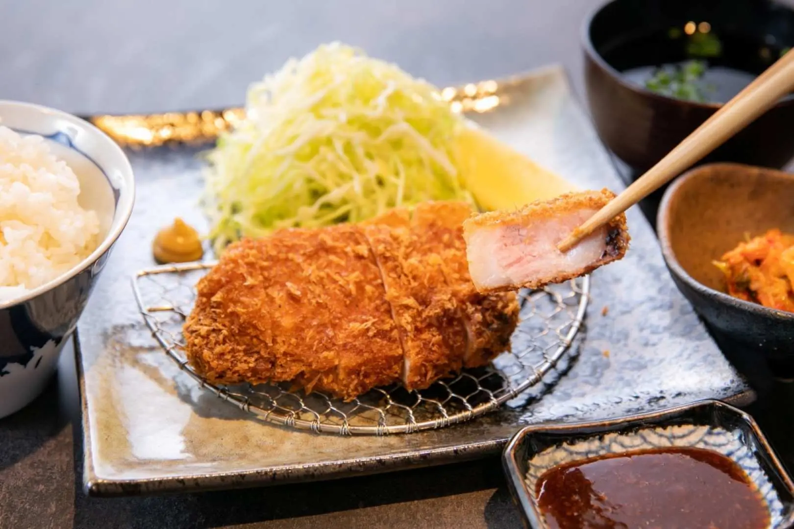 An appetizing Japanese Tonkatsu set meal, featuring golden crispy pork cutlets served with shredded cabbage and white rice, a must-try local delicacy in Kyushu.