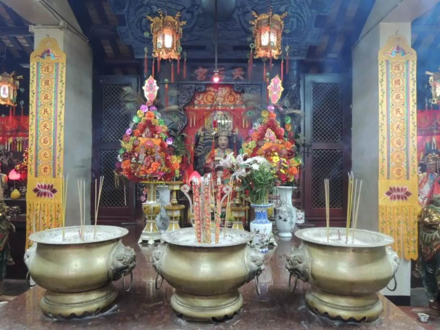 大埔林村寺廟內景，供桌上擺滿鮮花祭品，香爐中插滿香支，信眾在此虔誠祈福。