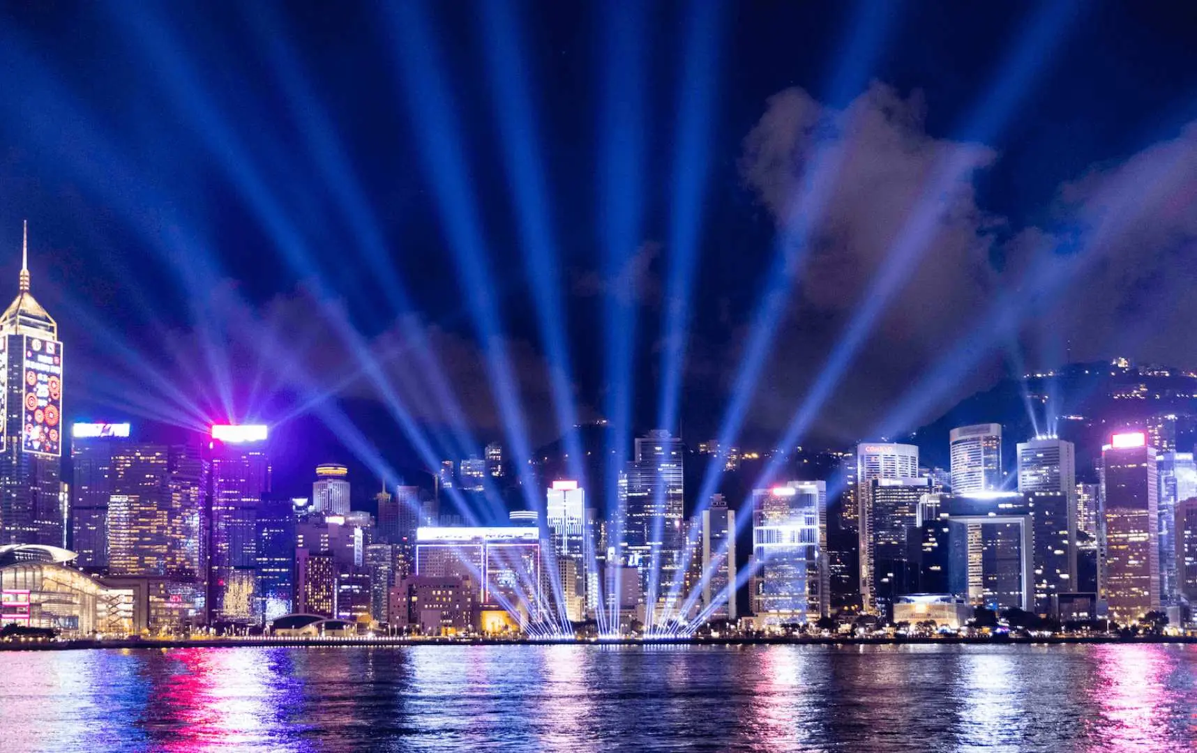 Hong Kong's Victoria Harbour night view with illuminated skyscrapers and beams from the Symphony of Lights show, showcasing the city's vibrant prosperity.