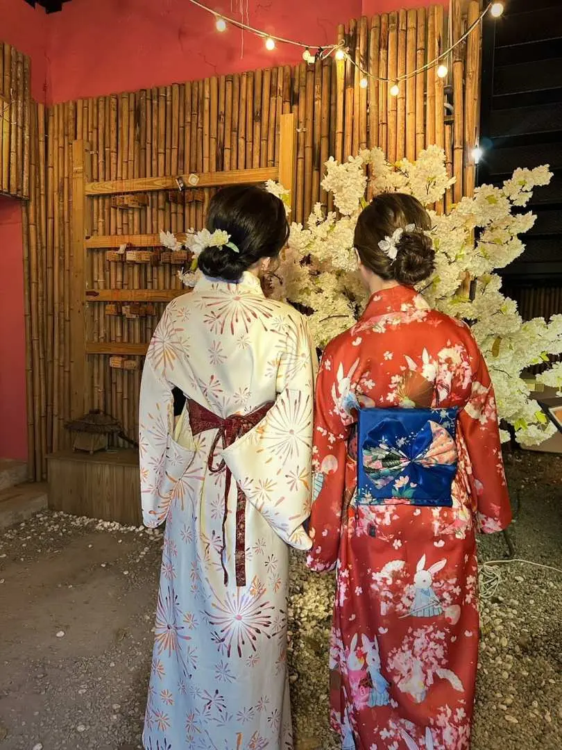 台北西门和服体验，两位顾客背影呈现精致和服与韩式发型，头饰点缀，在日式花墙前留影。