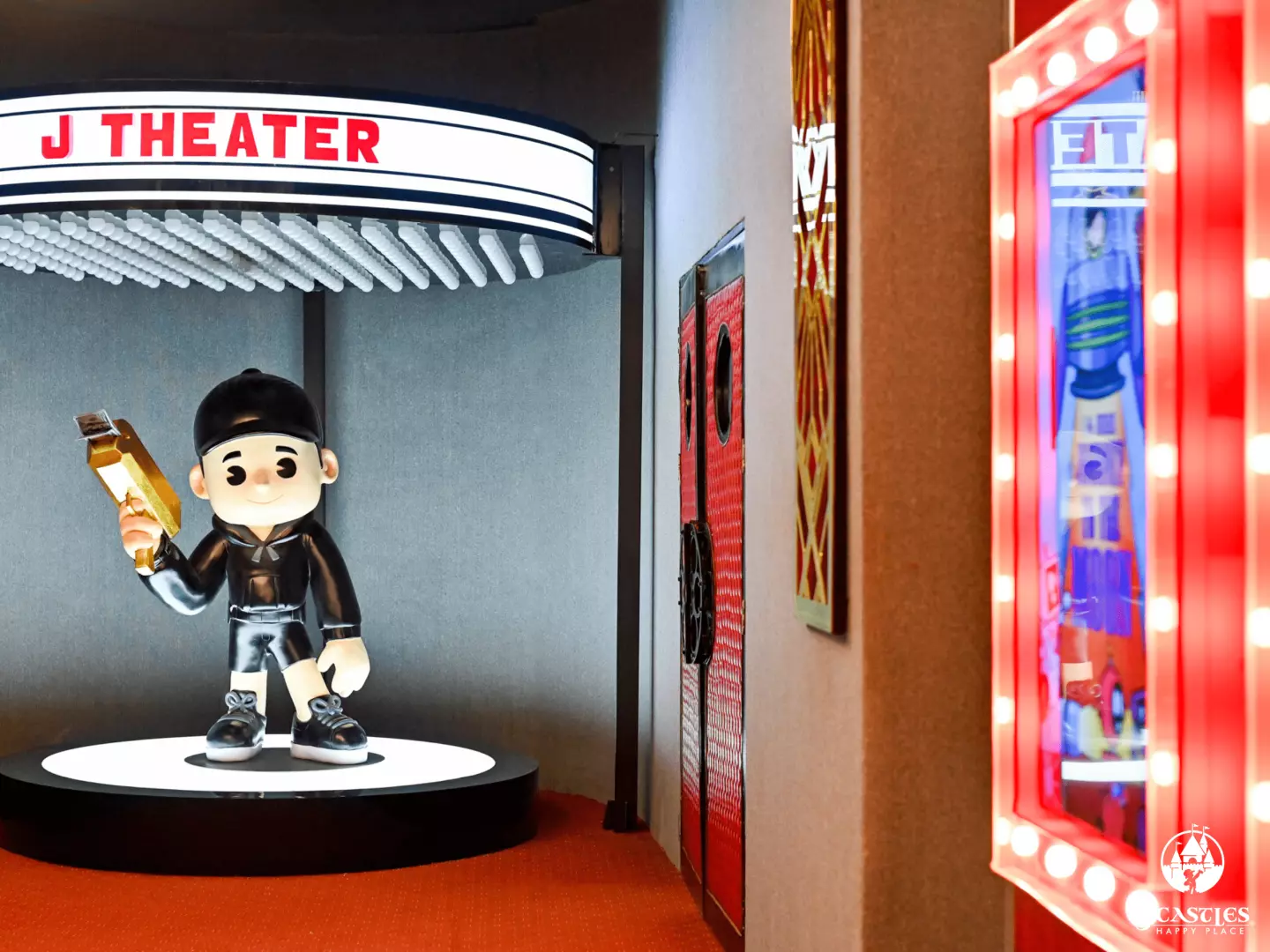 The captivating entrance to JCastles' J Theater, featuring a large, animated character statue on display and brightly lit showcases displaying unique figurines and costumes.
