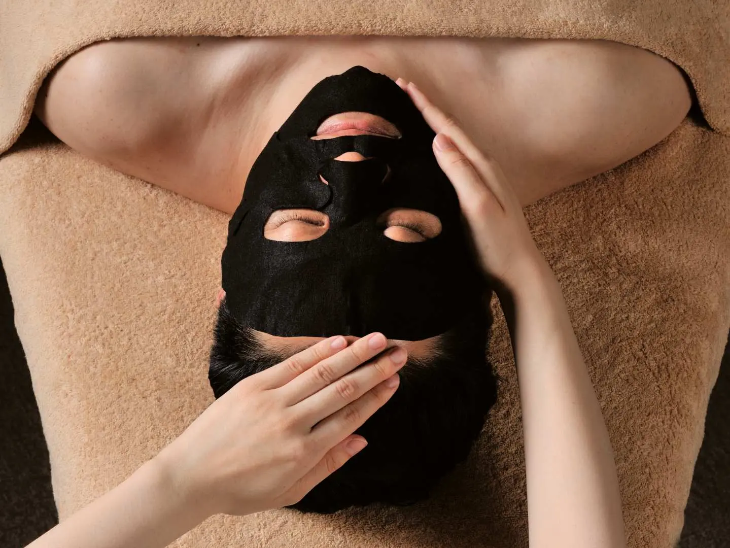 A client at a Ginza, Tokyo salon experiencing a unique black facial mask, possibly a CBD carbonic acid pack, designed to improve circulation, deeply nourish the skin, and provide relaxation.