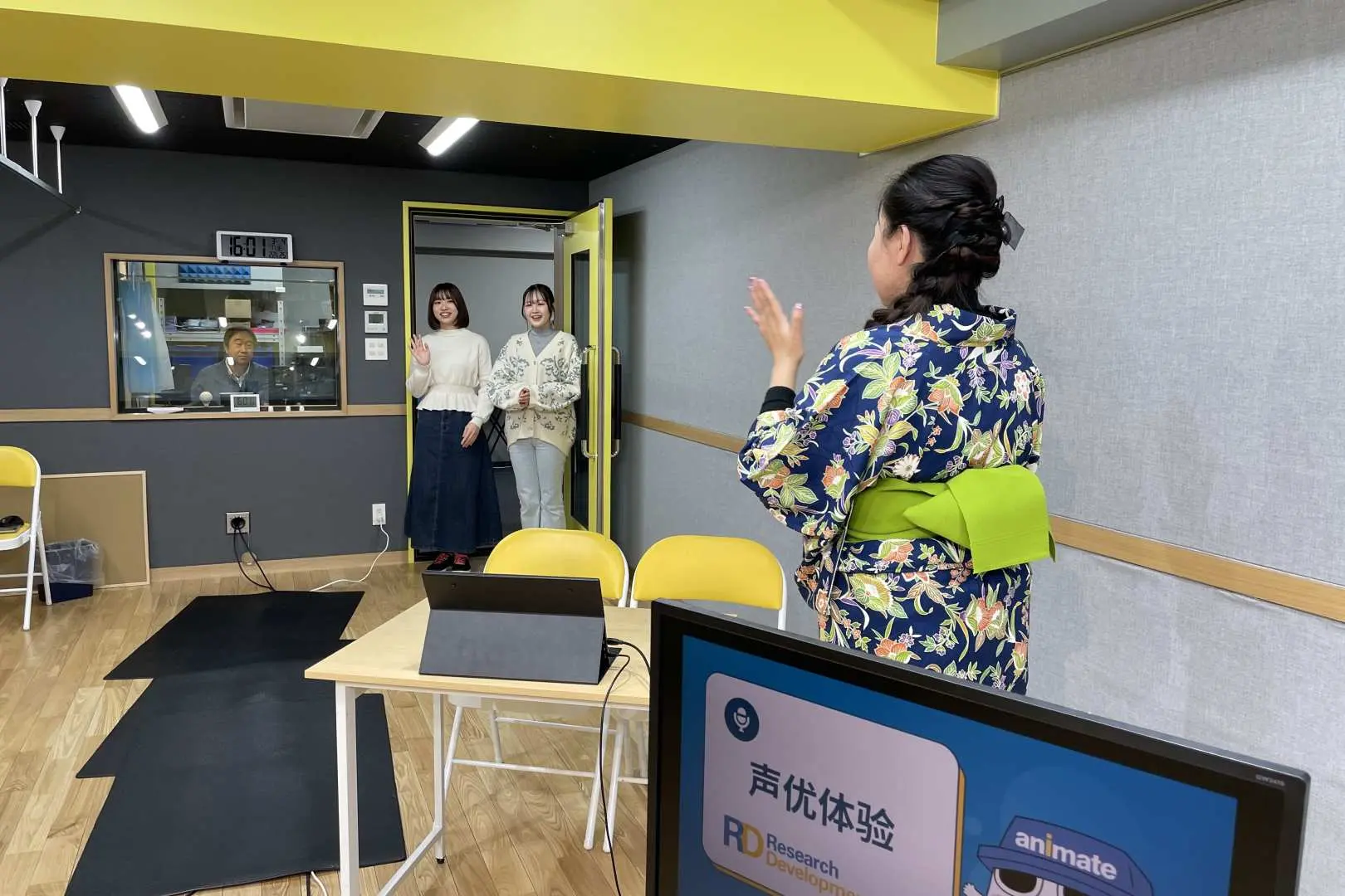 In the Tokyo Ikebukuro voice acting studio, a professional voice actor instructor guides two participants through a practical voice acting exercise, offering real-time vocal coaching.