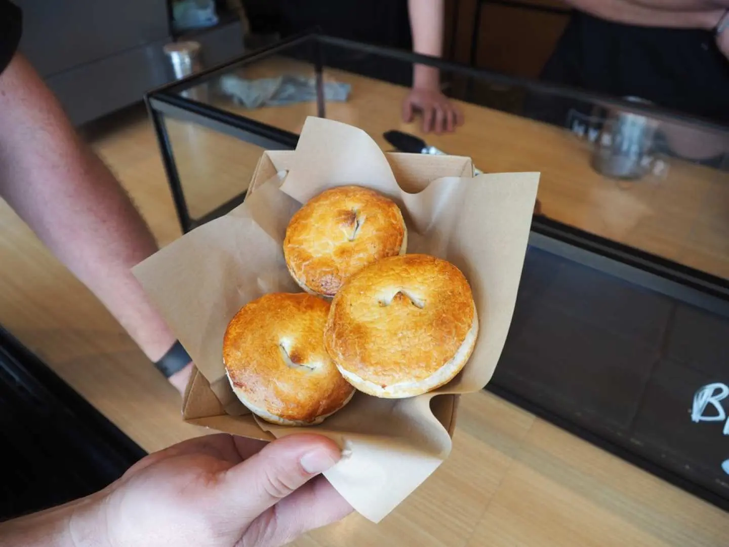 ガイドが手に持ったマリックビルで手作りされたオーストラリア風味の軽食3つを観光客に提供し、シドニーの多様な食文化を体験してもらっている様子。