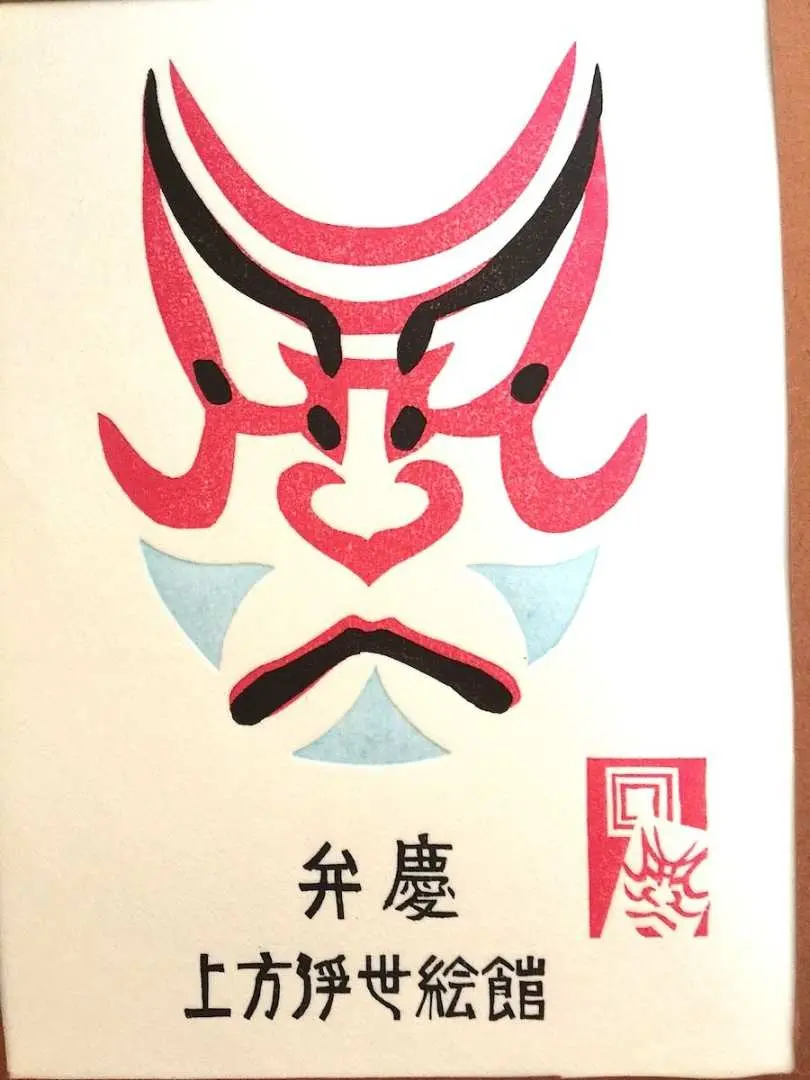 精美的浮世繪版畫成品，紅色與黑色的歌舞伎臉譜設計，下方印有「上方浮世繪館」，是獨特紀念。