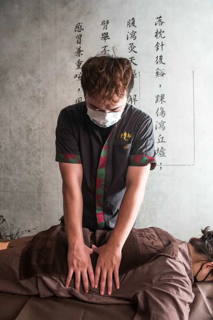 專業按摩師在台南不老松足湯為顧客進行背部放鬆按摩，專注於舒緩腰背緊繃，提供全面的身體療癒。