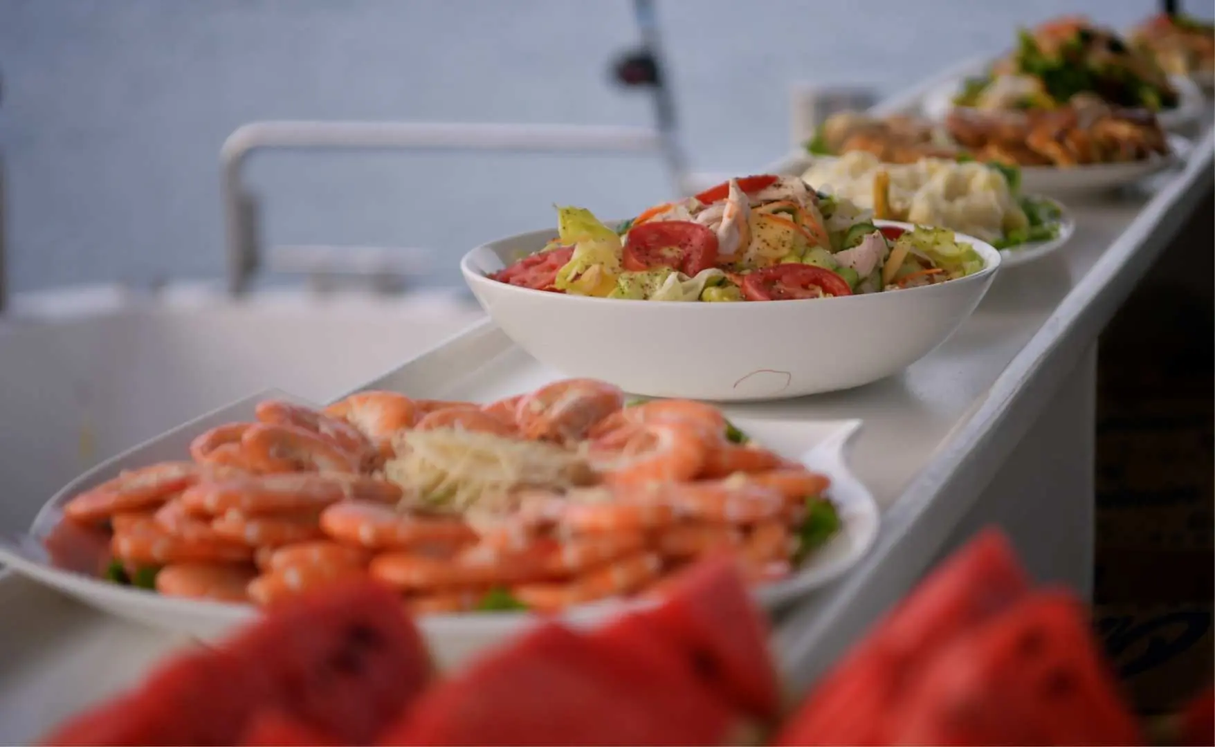 Elegant seafood buffet table on the yacht, featuring fresh shrimp, salads, and various delicacies for guests to savor a grand feast at sea.