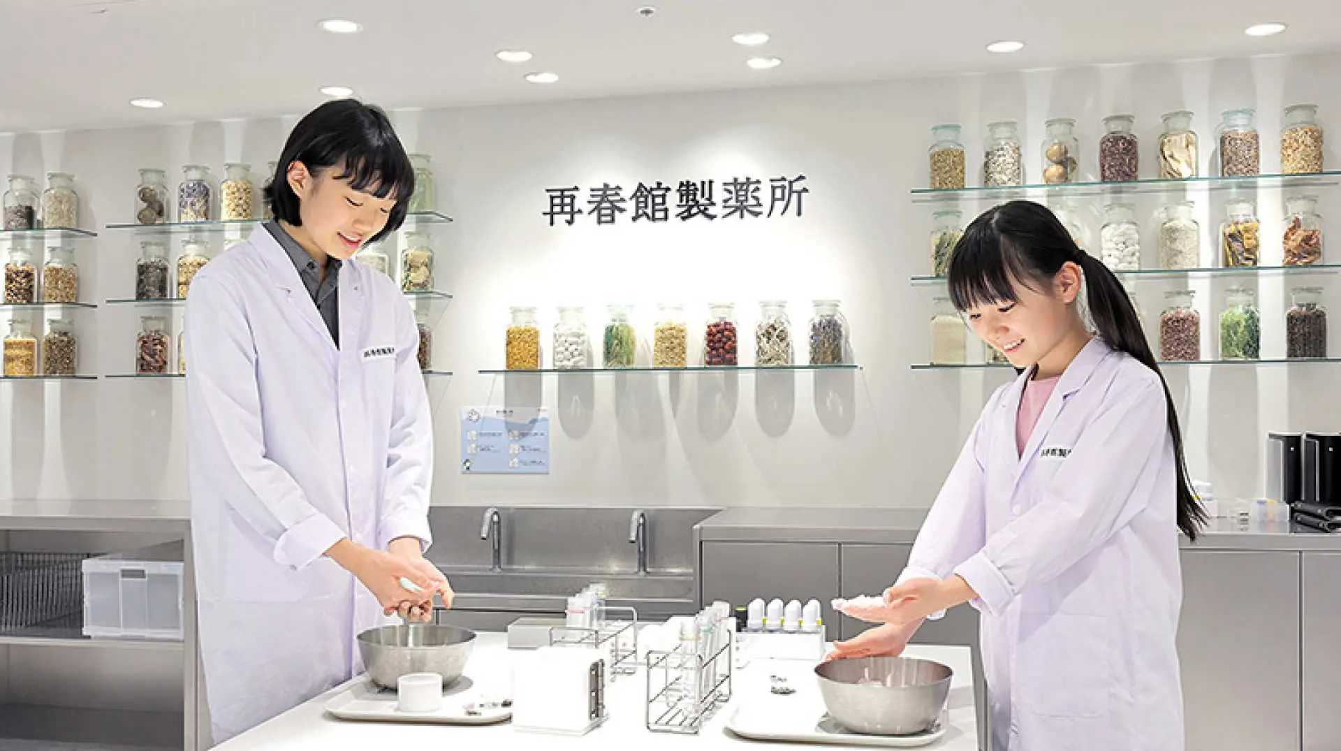 キッザニア福岡で女の子たちが薬剤師を体験。白衣を着て製薬工場で薬を調合し、薬の知識と科学への興味を育む。