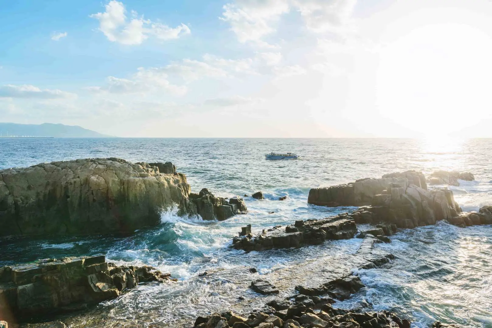 日本福井東尋坊海蝕懸崖的黃昏美景，金色的夕陽餘暉灑落在崎嶇的柱狀玄武岩和拍打的浪花上，呈現出獨特的壯麗風光。