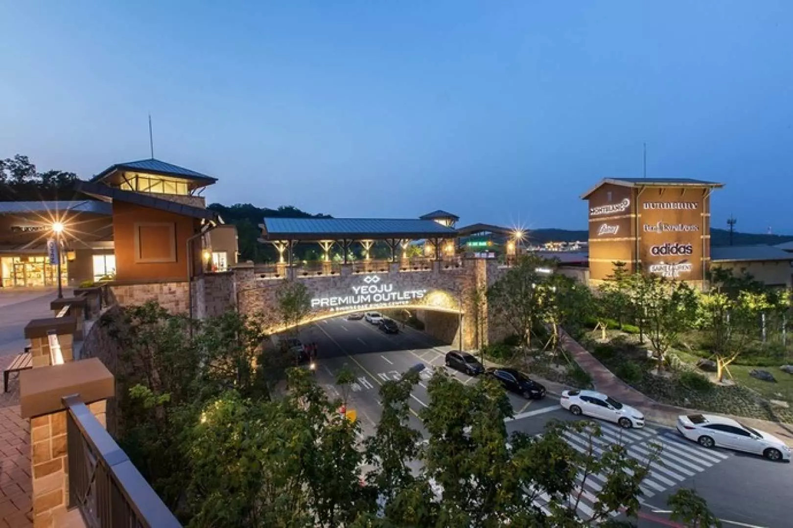 韓國驪州高級名牌折扣購物中心夜景，建築與標誌燈火通明，遊客可在此享受高端購物樂趣，選購各式奢侈品牌商品。