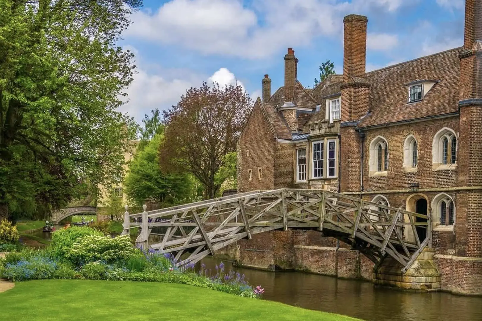 Queen's College's Mathematical Bridge at Cambridge University, a uniquely designed wooden bridge spanning the River Cam, surrounded by lush green lawns, embodying the blend of British countryside and academic elegance.