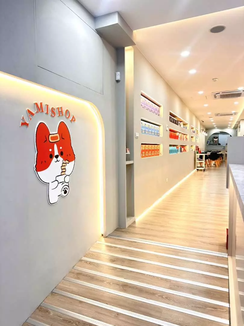 西門町YAMI SHOPの明るく清潔な店内通路に、かわいい店舗ロゴが描かれ、空港送迎予約者向けの無料荷物預かりと8割引特典を提供。