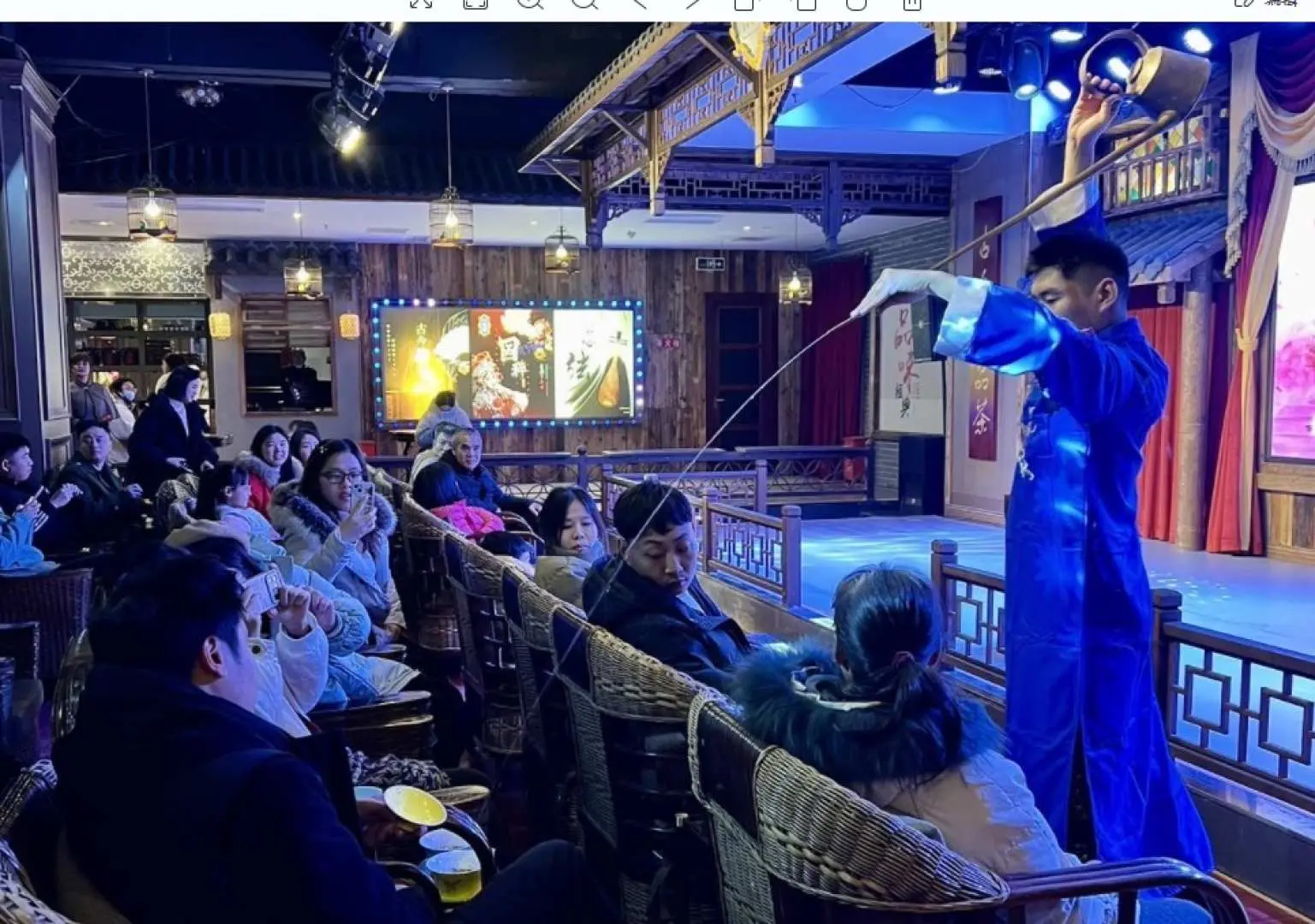 重庆1941茶馆剧院内，茶师穿梭于观众席间表演盖碗茶艺，展现传统茶文化与独特倒茶技艺。