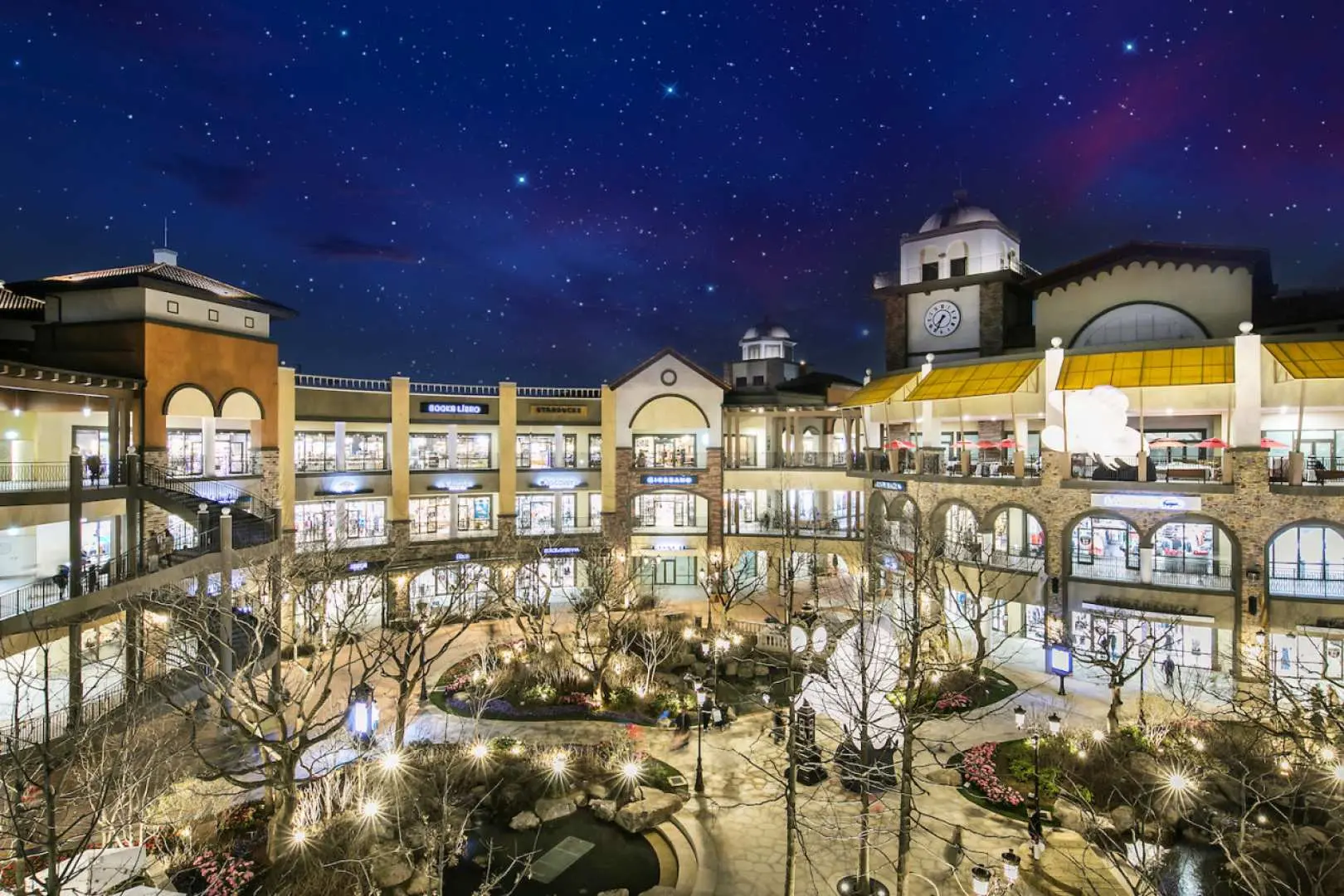 Siheung Premium Outlets in Korea with a captivating night view. Buildings and walkways are illuminated with dazzling lights, creating a romantic shopping atmosphere, attracting visitors to enjoy evening fashion and gourmet experiences.