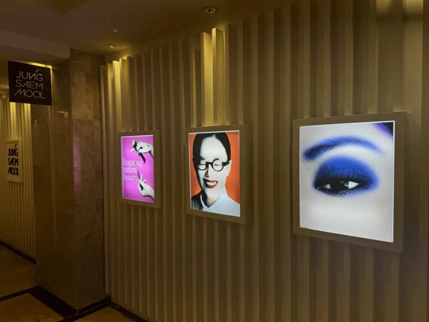 Entrance hallway of JUNGSAEMMOOL Inspiration Avenuel branch at Lotte Department Store Seoul, featuring stylish advertisements for professional makeup, hair, and skincare, guiding customers to a premium K-Beauty experience.