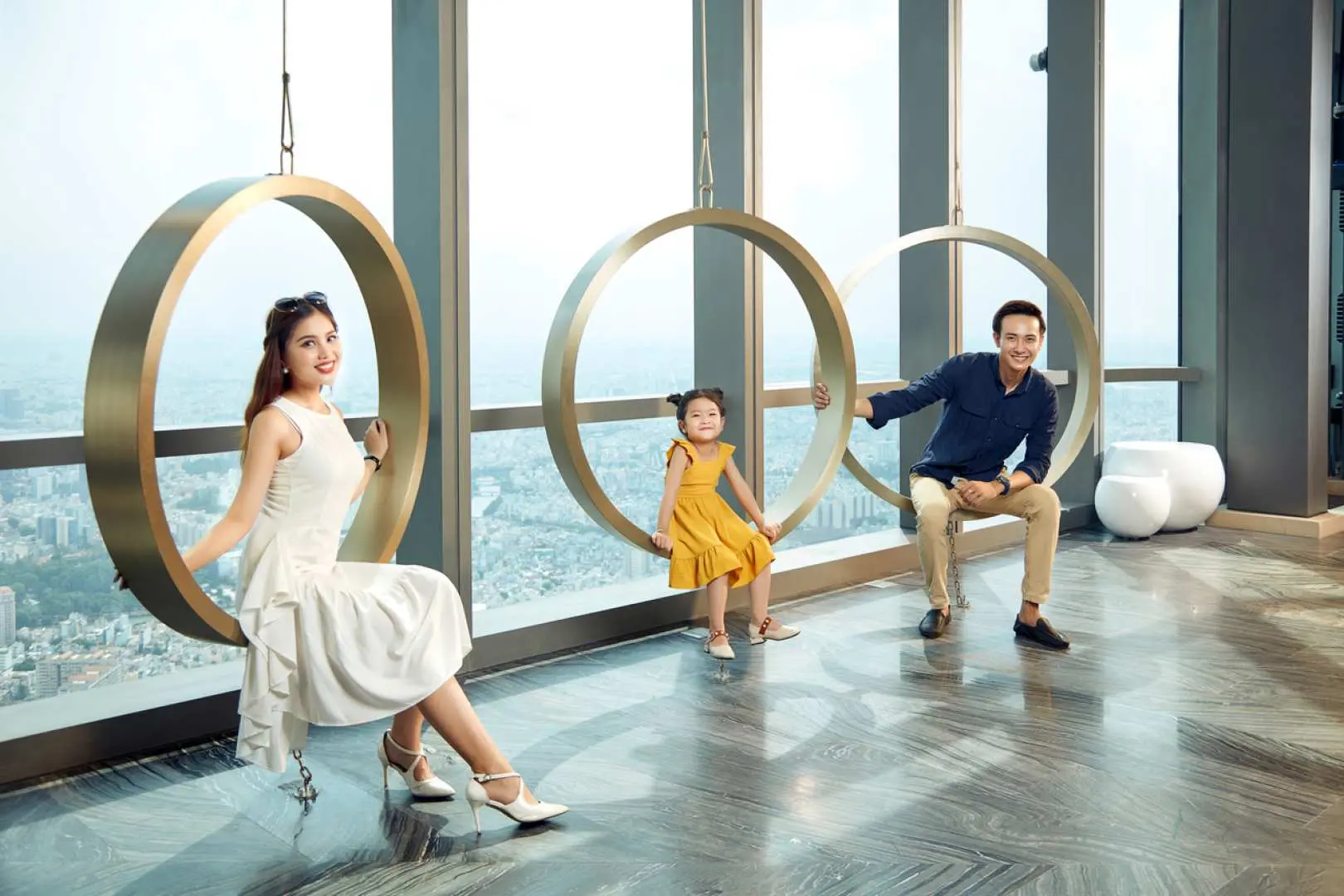 一家人在越南胡志明市地標81觀景台的特色圓環座椅上，面帶微笑，享受高空俯瞰城市美景的歡樂時光。