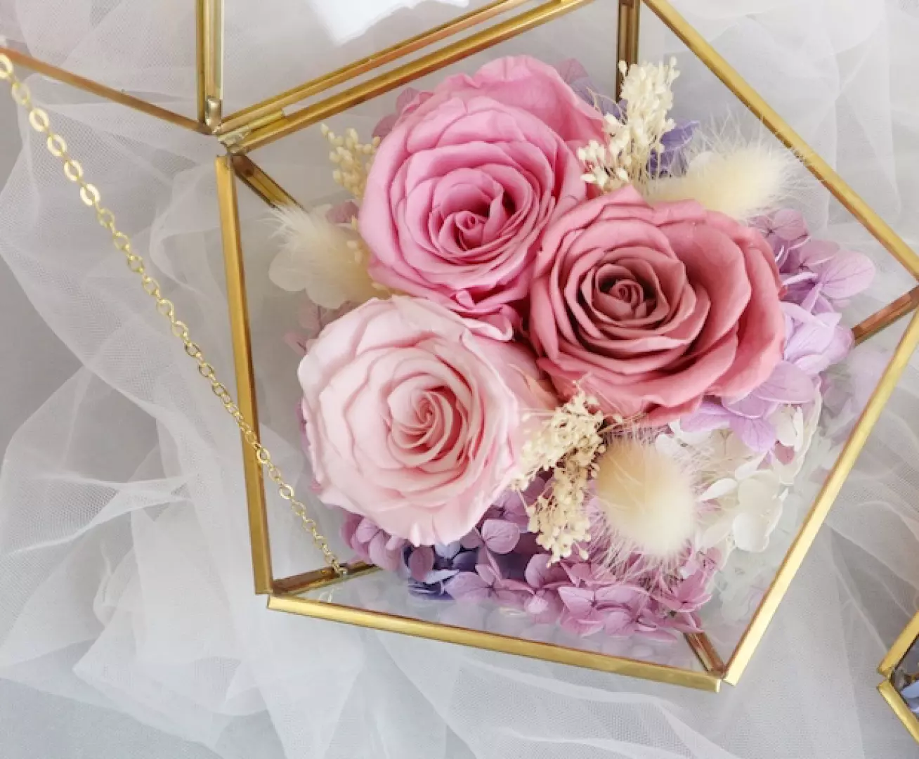Close-up of preserved flowers inside a golden geometric glass box, featuring three delicate pink preserved roses exquisitely arranged with purple hydrangeas, showcasing the refined artistry of Myosotis.flower Kwun Tong DIY floral craft.