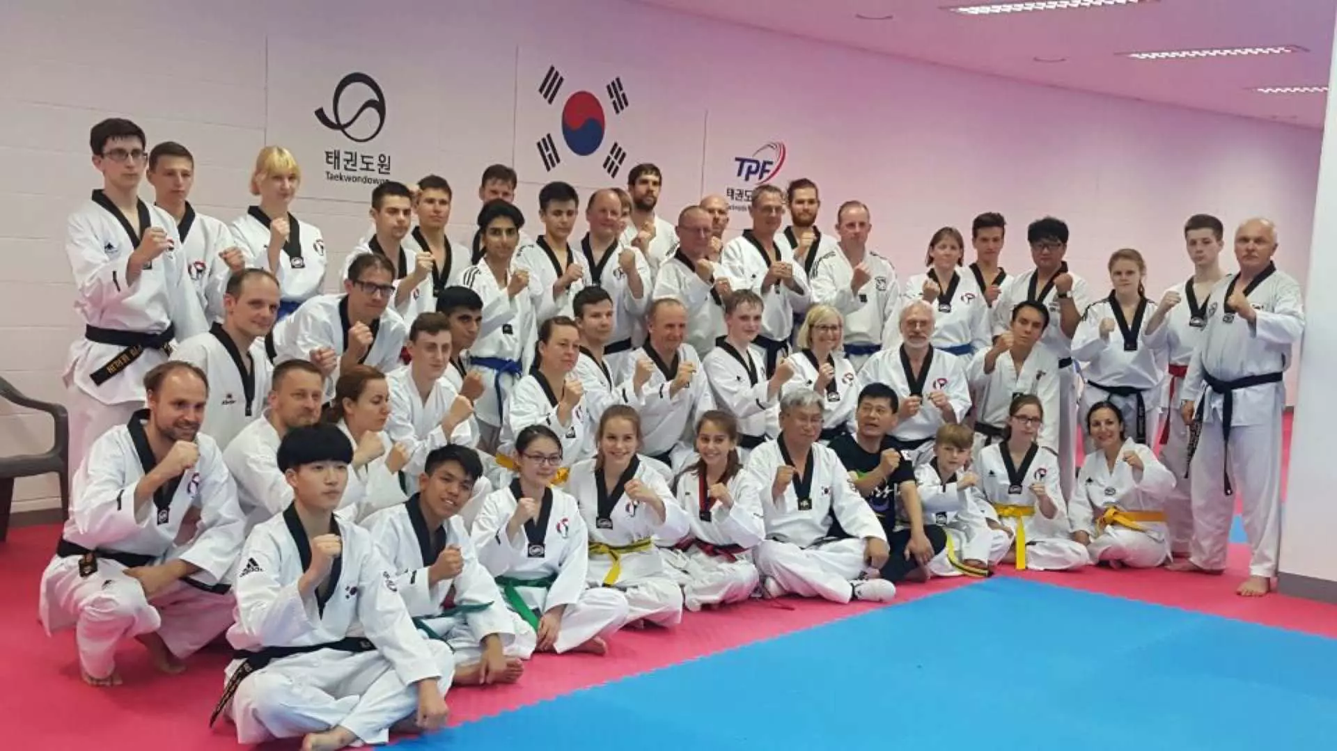 韓国大邱テコンドー格闘技体験コースの生徒と教官が大勢で集合写真を撮り、国際的な生徒たちが武術文化を学ぶ情熱と活気を表しています。