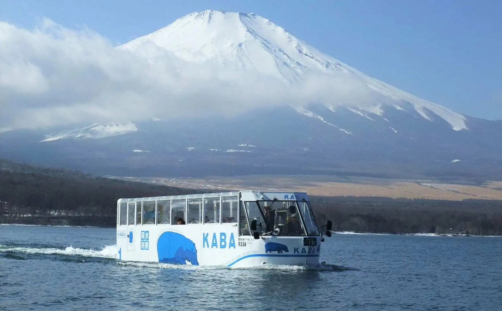 KABA水陸兩棲巴士在山中湖寬闊水面破浪前行，遠方是雄偉的白雪富士山。