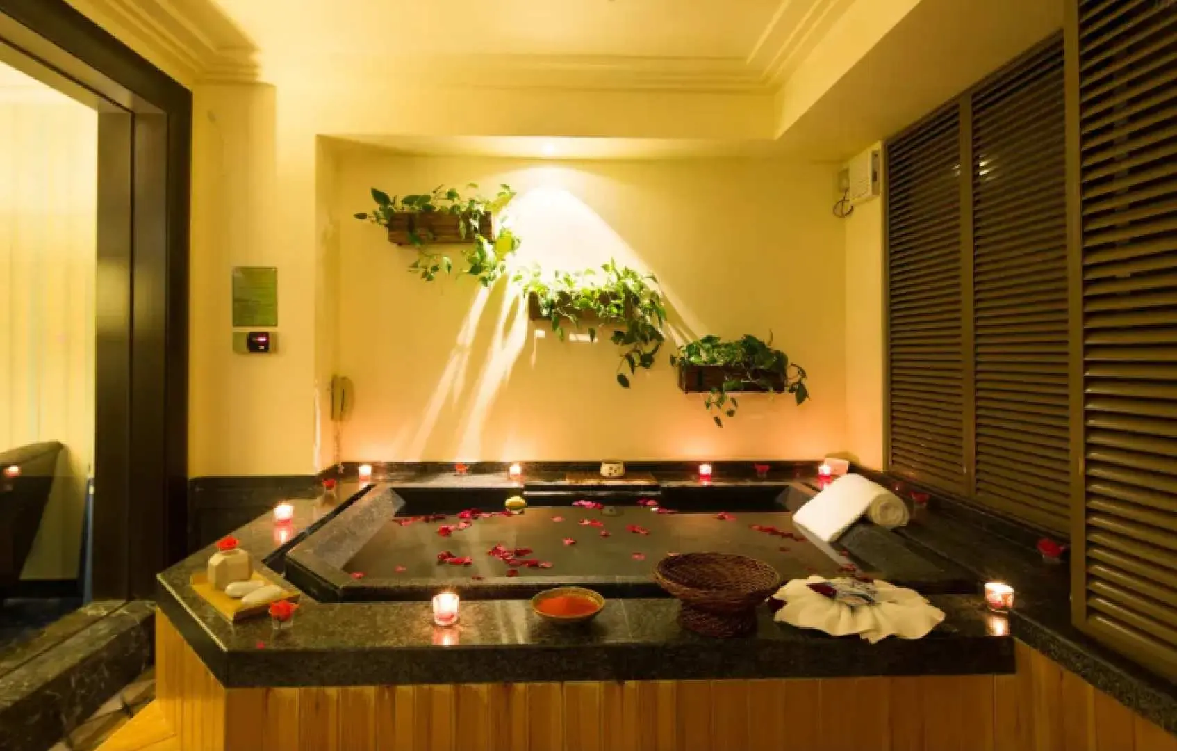 อ่างอาบน้ำพุร้อนส่วนตัวที่โรงแรม Chunhuiyuan Hot Spring ประดับด้วยกลีบกุหลาบและเทียน มอบประสบการณ์ผ่อนคลายที่โรแมนติกและเป็นส่วนตัว.