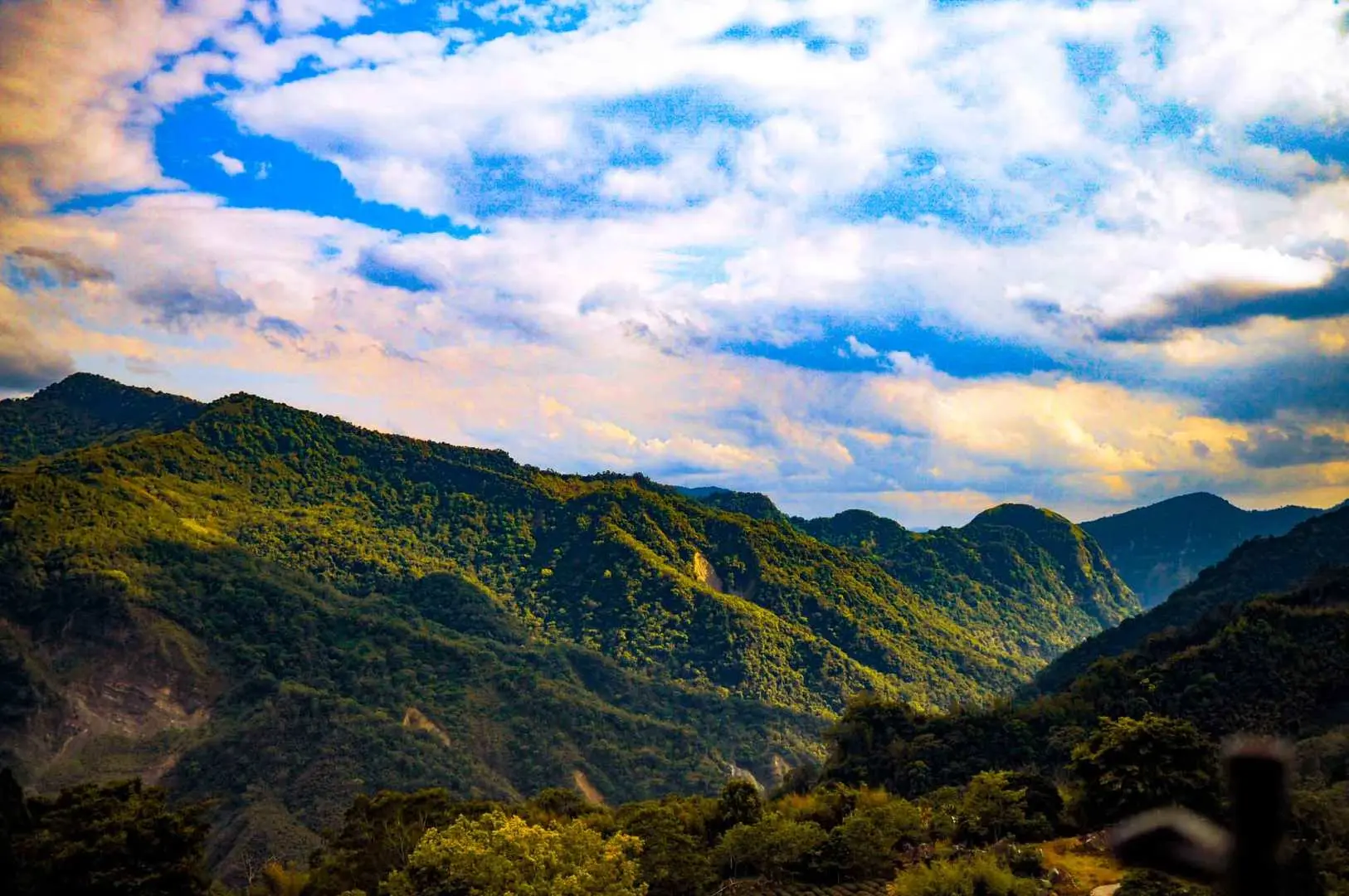 阿里山广阔的山峦叠翠全景，在蓝天白云下显得气势磅礴，展现嘉義包车一日游的壮丽自然风光。
