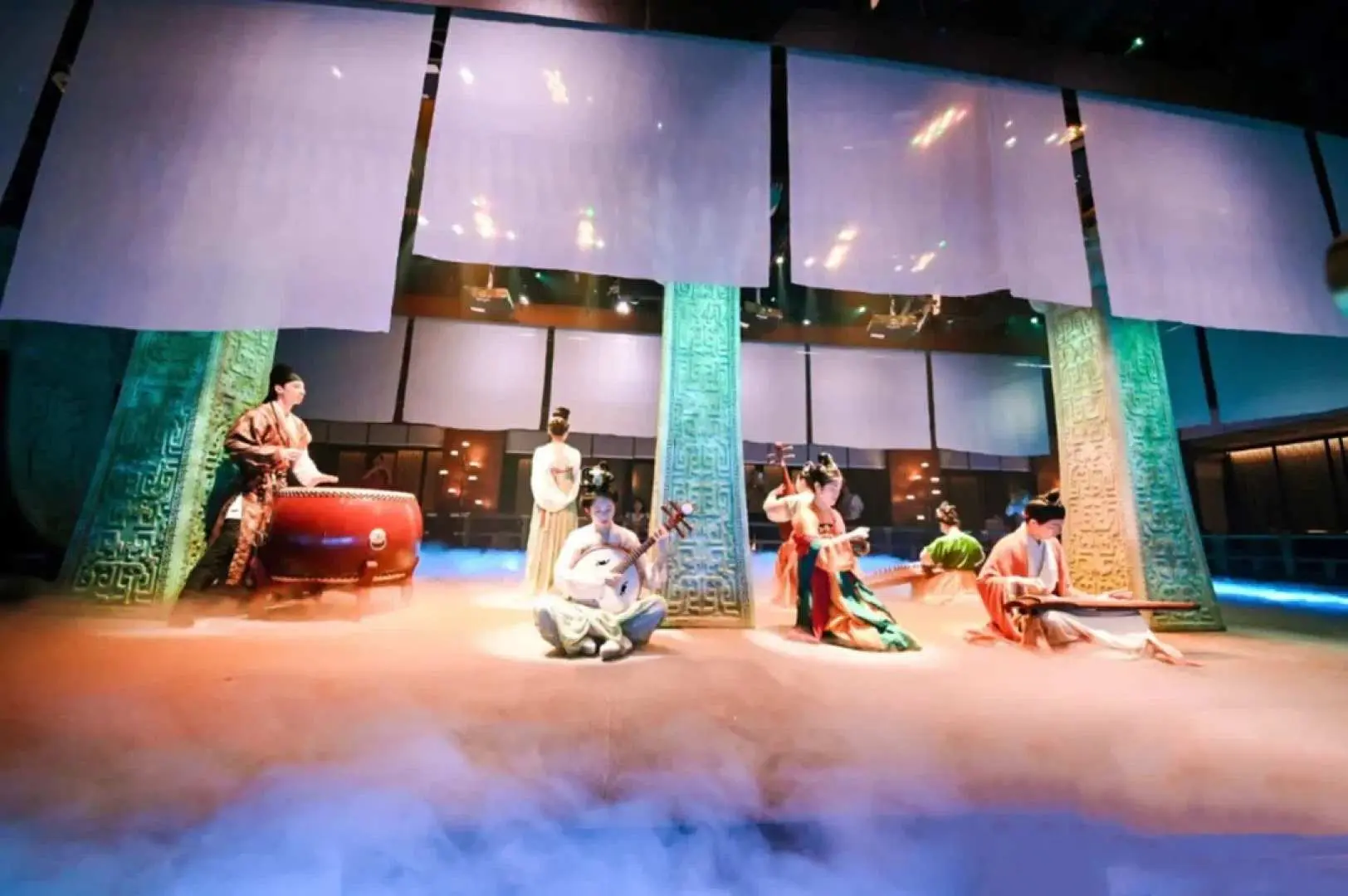 Musicians in ancient costumes play traditional instruments amidst mystical mist at Beijing Palace Banquet's themed performance, showcasing rich dynastic cultural characteristics in a dreamy setting.