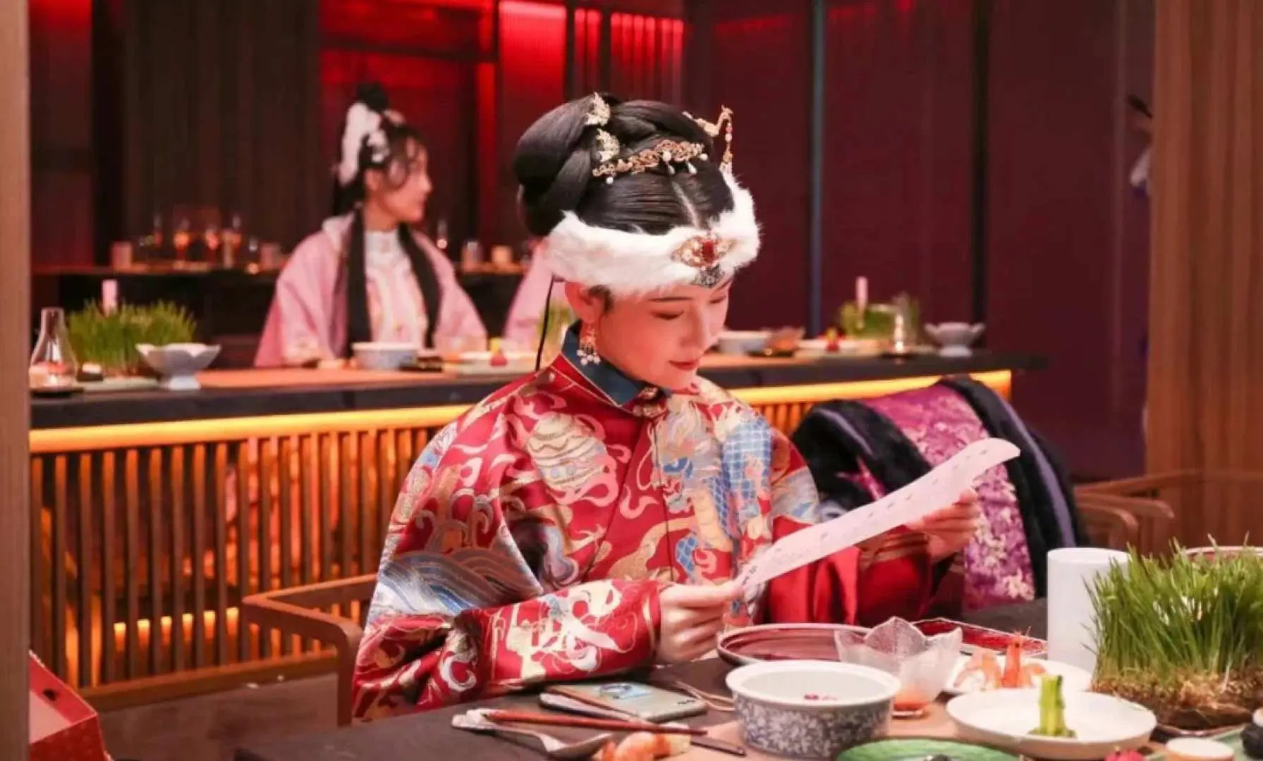 A guest in elaborate Hanfu and headpiece, role-playing as a royal, enjoys the interactive dining experience at Beijing Palace Banquet, feeling transported to ancient court life.