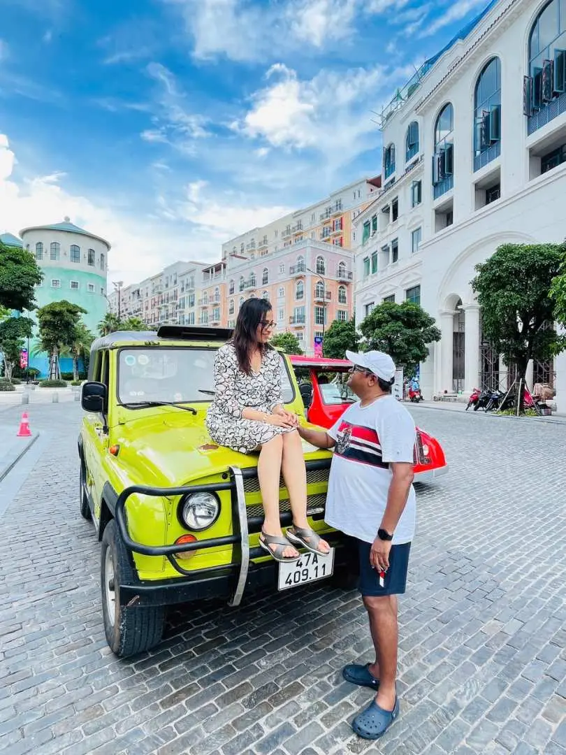 一對情侶在富國島現代化的城市街景中，與亮黃色敞篷吉普車互動，享受時尚與島嶼探險兼備的旅程。