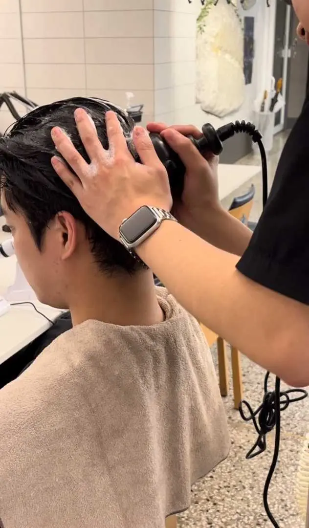 JUNO HAIR professional stylist provides meticulous haircutting service for a male client, focusing on the nape hairline to create a neat, stylish look.