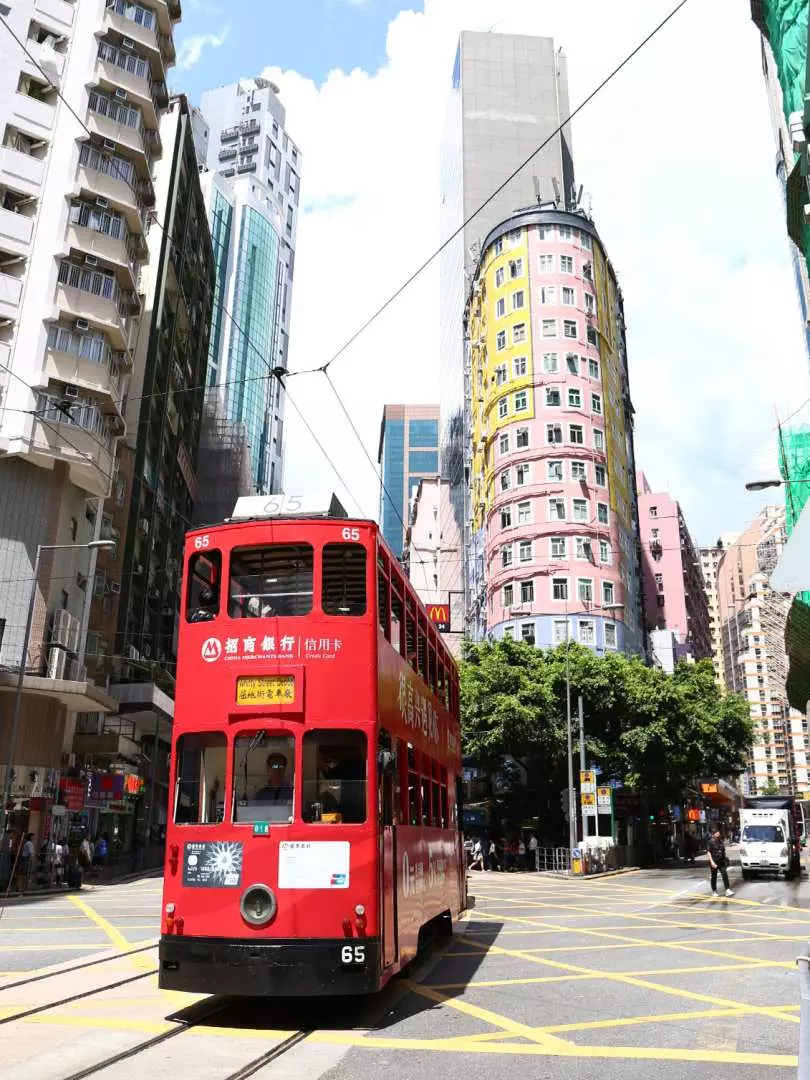 香港標誌性嘅紅色雙層「叮叮」電車行駛於繁忙嘅城市街道上，周圍高樓林立，提供獨特嘅香港懷舊交通體驗。