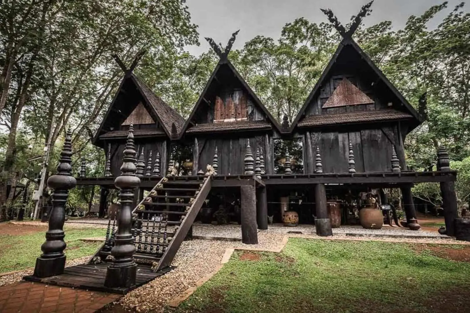 清萊黑屋（Baan Dam）多棟深色傳統泰式木屋建築群，展現Thawan Duchanee獨特的藝術風格。