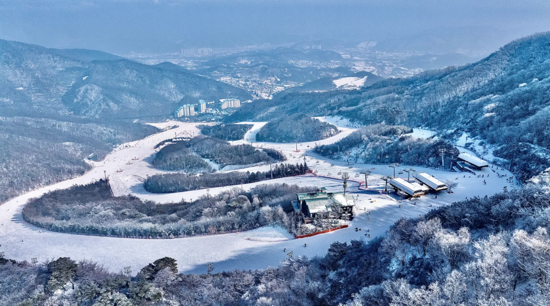 韩国昆池岩滑雪场白天全景航拍图，展示了多条雪道、现代化的缆车和度假村建筑，是首尔出发的热门滑雪胜地。