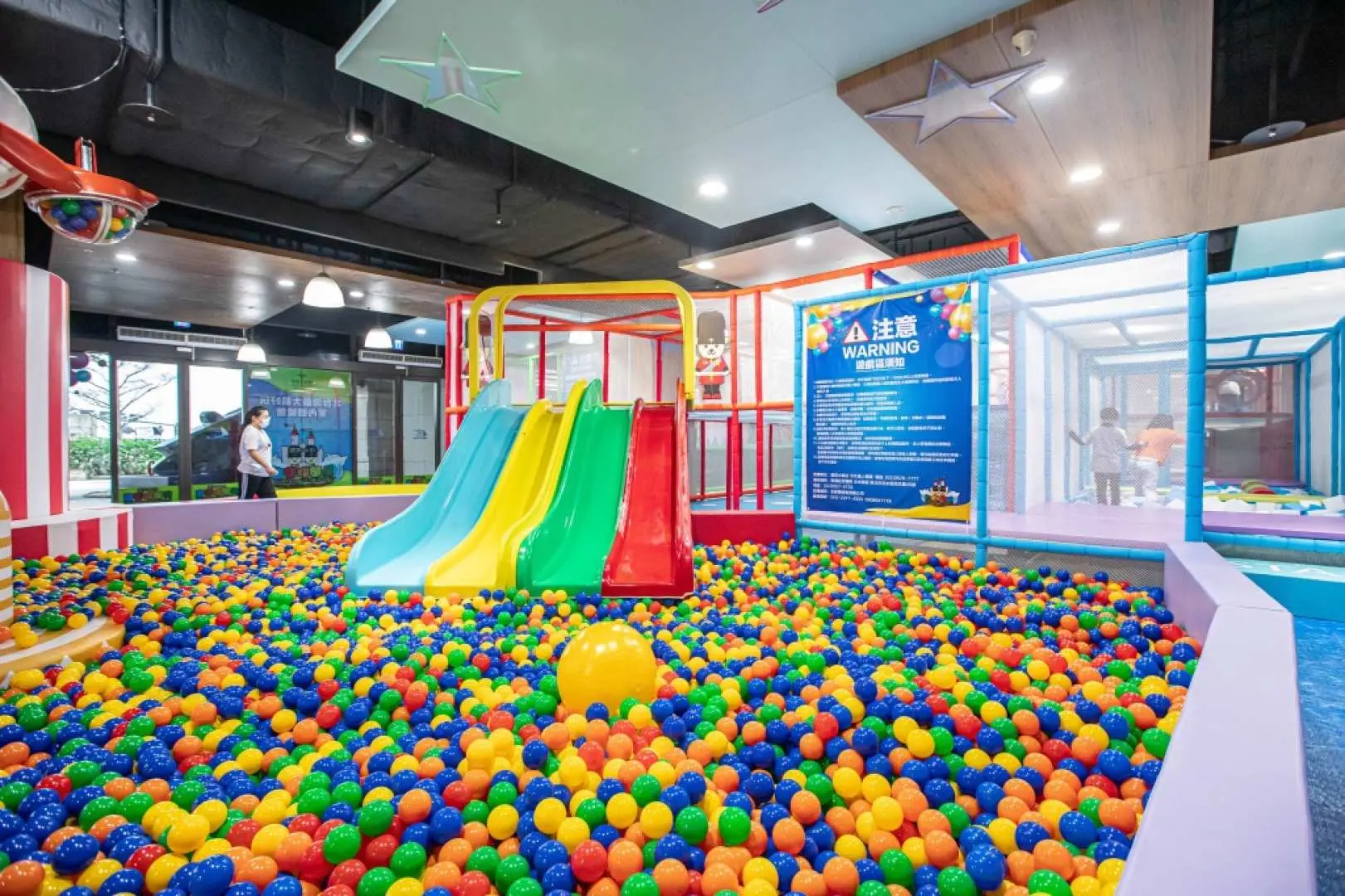 Children enjoying the indoor amusement park at New Taipei POPA Parent-Child Physical Activity Center, playing in a colorful ball pit with transparent tunnels connecting to climbing areas and multiple slides in the background.