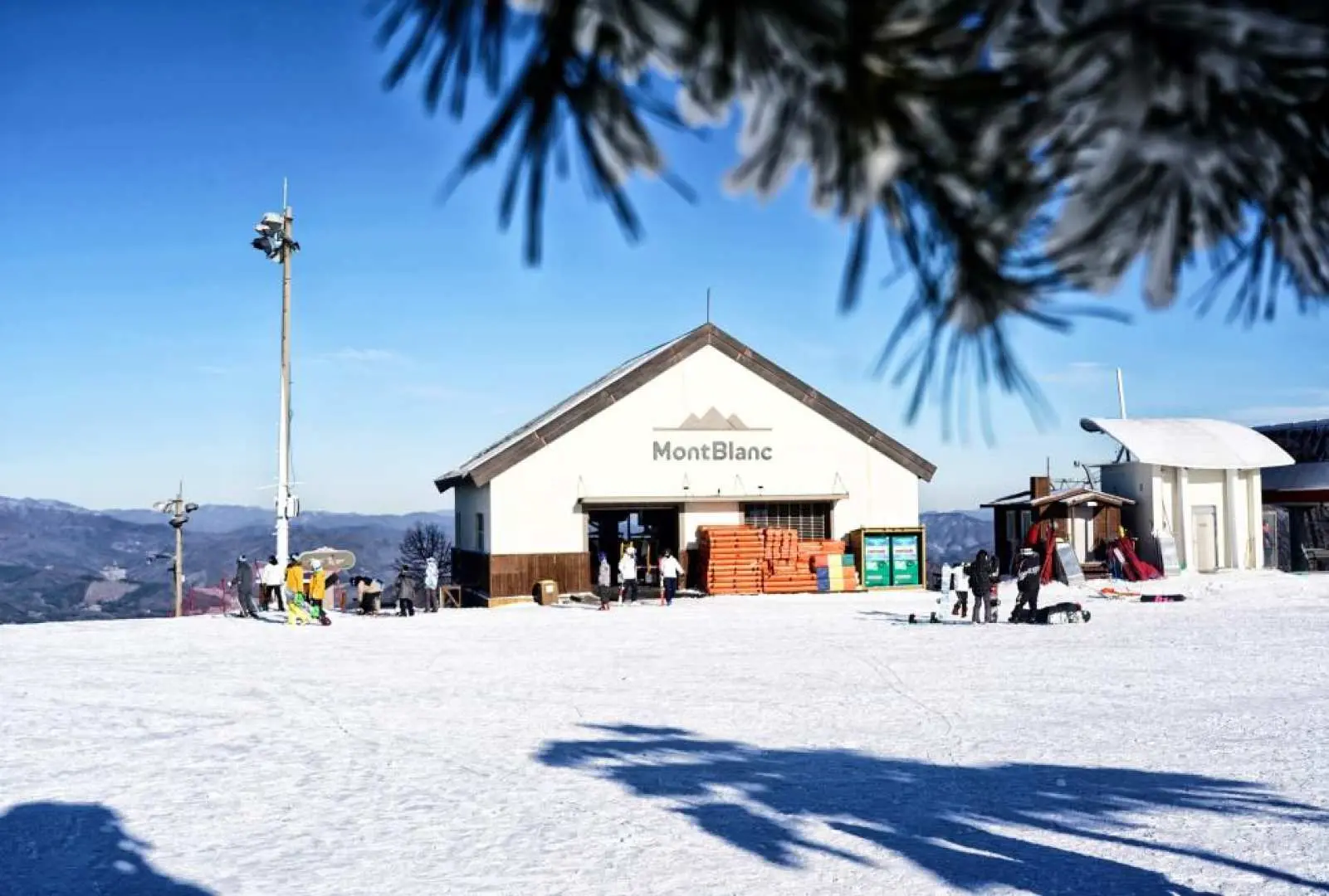 平昌鳳凰雪上樂園的「Mont Blanc」山頂小屋，被白雪覆蓋的建築與前景霜凍樹枝，營造出冬季滑雪勝地的寧靜氛圍。