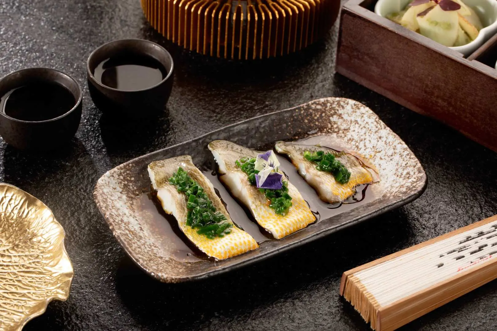 青島蘭齊宴賦精緻宮宴主菜，三片鮮美魚柳佐以翠綠醬汁與紫色花卉點綴，盛於雅緻餐盤，展現中華飲食文化的匠心。