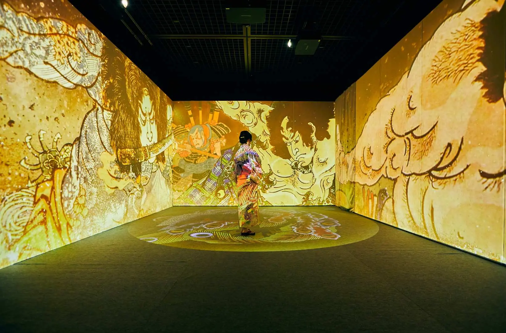 高雄浮世繪展中的沉浸式體驗，訪客站在360度投影空間中央，周圍牆壁與地板流動著動態浮世繪人物與神話圖案。