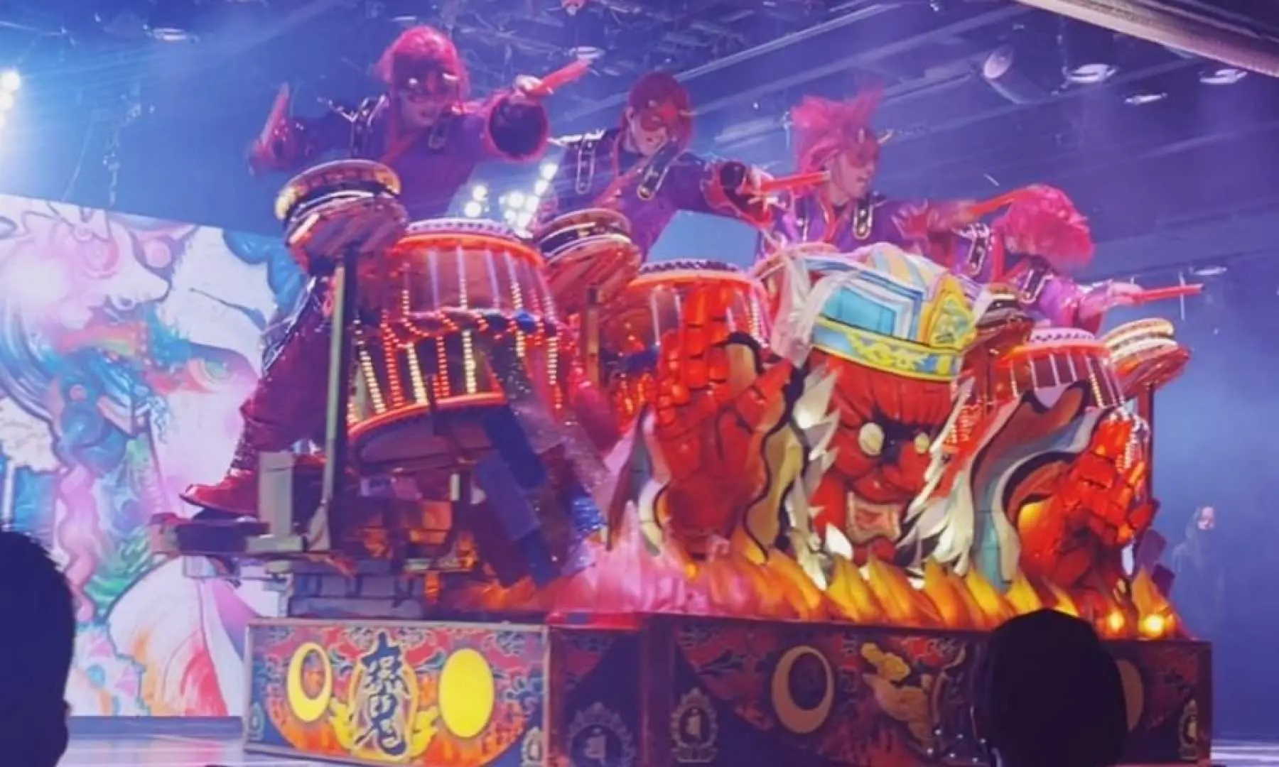 Robot float drumming performance at Samurai Restaurant in Shinjuku, Tokyo, where dancers energetically play drums atop a massive red demon-head float, combined with intense lighting for a stunning visual impact.