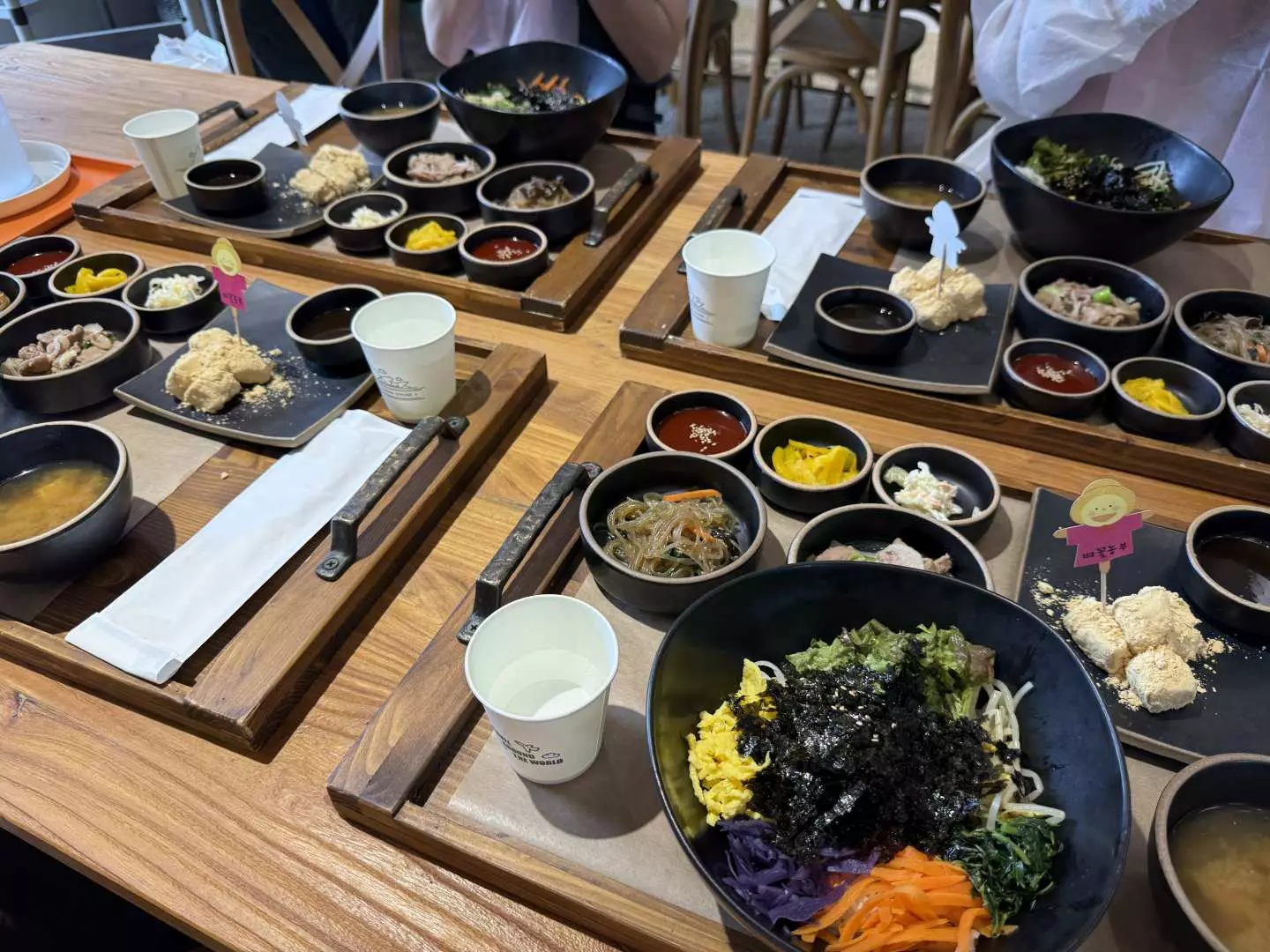 豐盛的韓國傳統農家韓餐，包含鮮豔的拌飯、多樣小菜與湯品，擺放在木製托盤上，讓遊客品嚐道地的韓國風味。