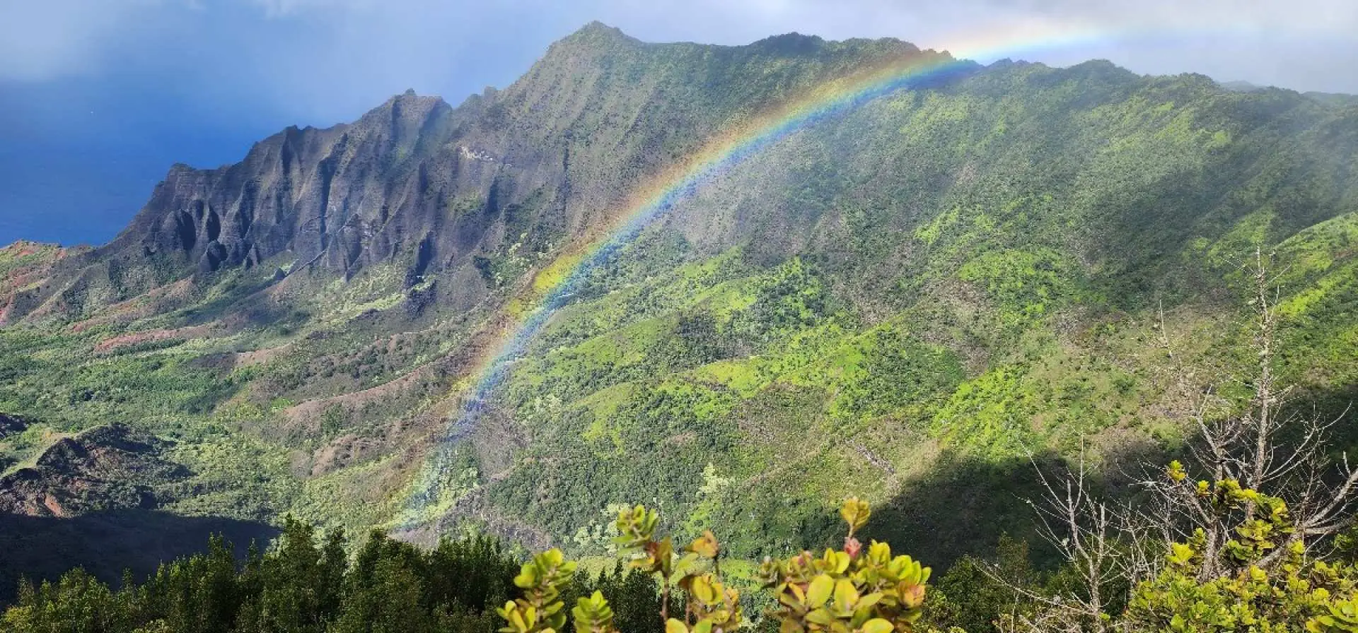夏威夷可愛島的壯麗山脈風光，一道絢麗彩虹橫跨茂密翠綠山谷，展現「花園島」考艾島的自然奇觀，適合一日遊探索。