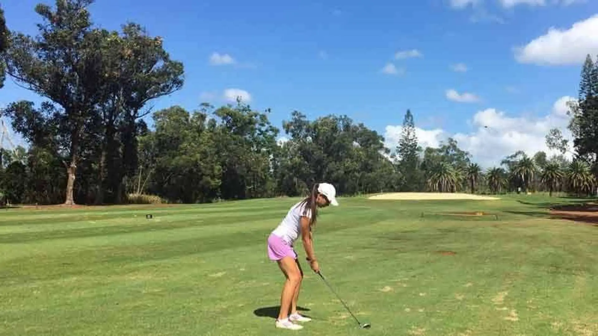 夏威夷米利拉尼高爾夫球場，一位女性高爾夫球手正準備在陽光普照的翠綠球道上擊球，享受18洞高爾夫樂趣。