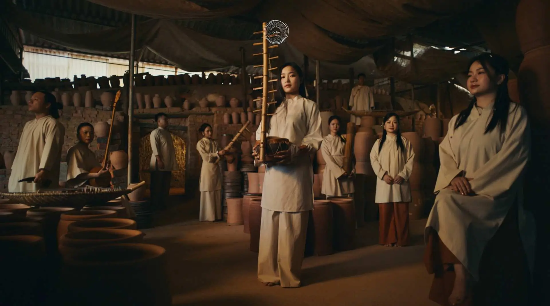 河内GOm演出前置场景，乐师们在陶瓷作坊中，身着传统服饰，手持陶瓷乐器，展现越南日常生活与文化的连结。