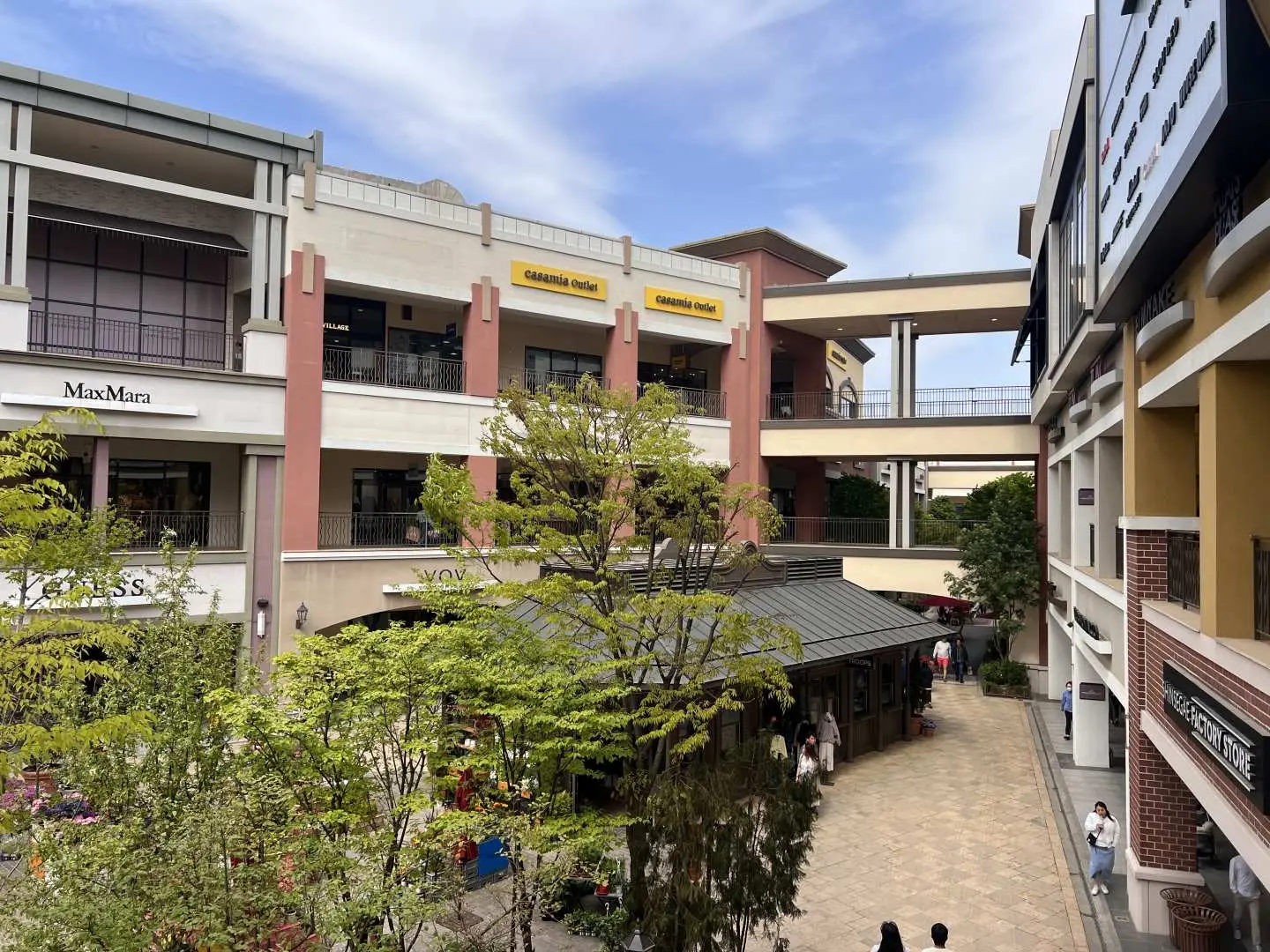 坡州名牌折扣购物中心现代感十足的建筑群，户外广场与商店街绿意盎然，营造出舒适的购物环境。