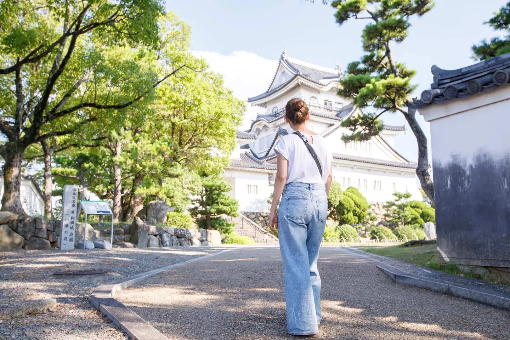 大阪岸和田城へと続く、伝統的な日本の風景と歴史的な壁に囲まれた風光明媚な小道を散策する訪問客。